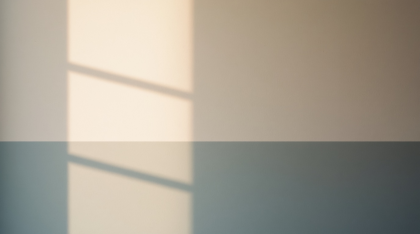 Soft daylight falling across a textured plaster wall in parchment and slate-blue tones